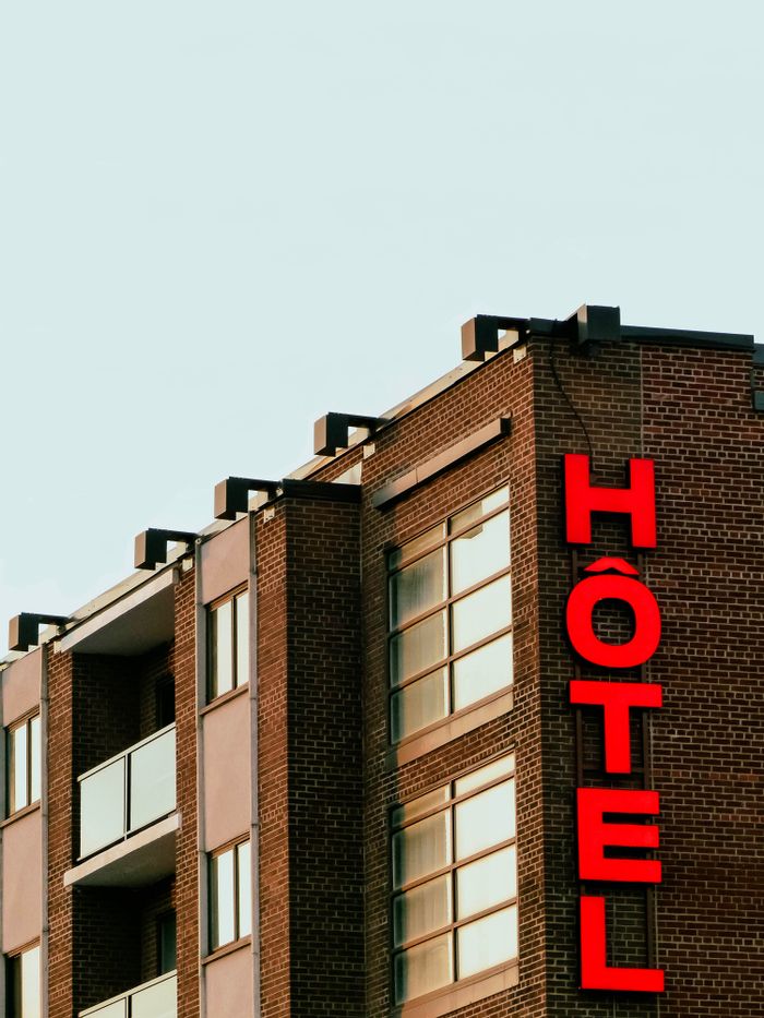 Brick hotel building with bold red signage in Montreal, Canada, under a clear sky.